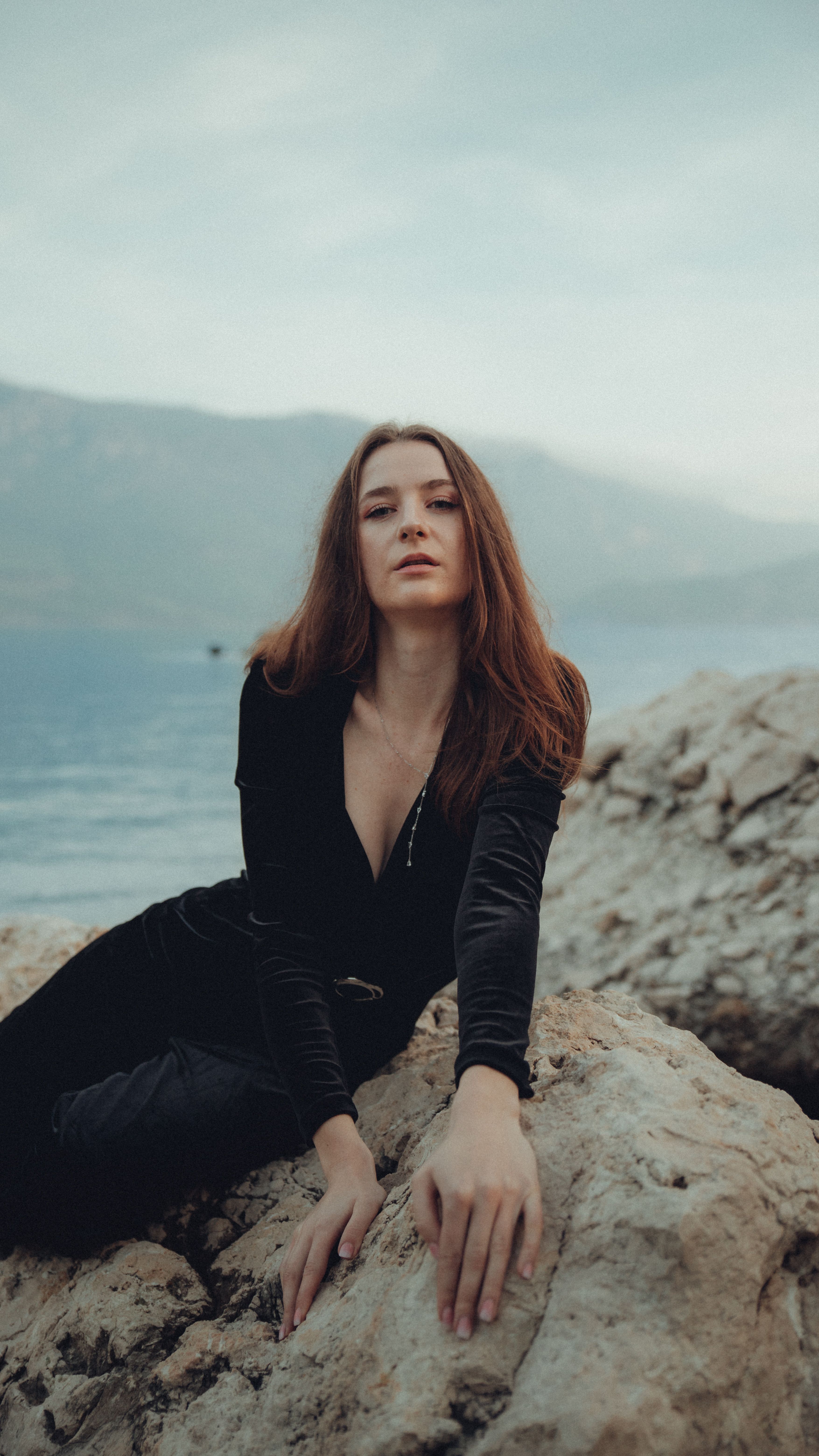Woman Posing on Rocks by Serene Lakeside · Free Stock Photo