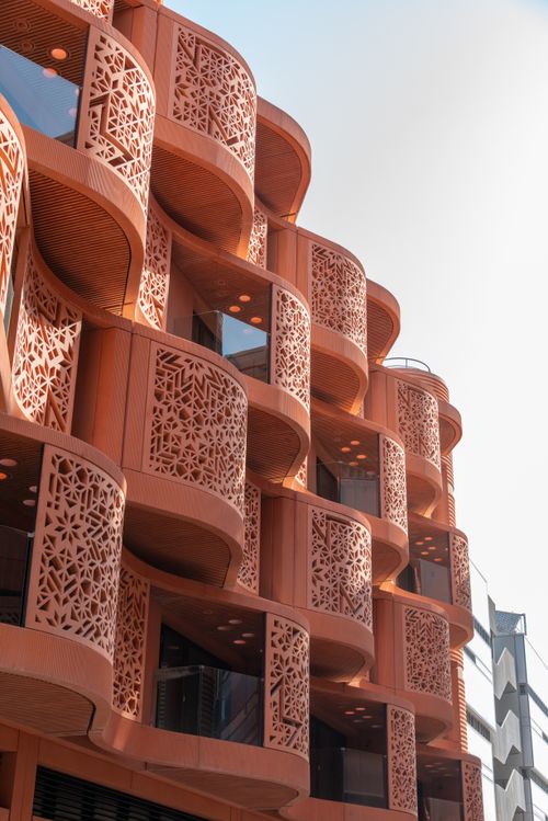 Free Low angle view of a striking modern building facade with intricate design patterns under bright sunlight. Stock Photo