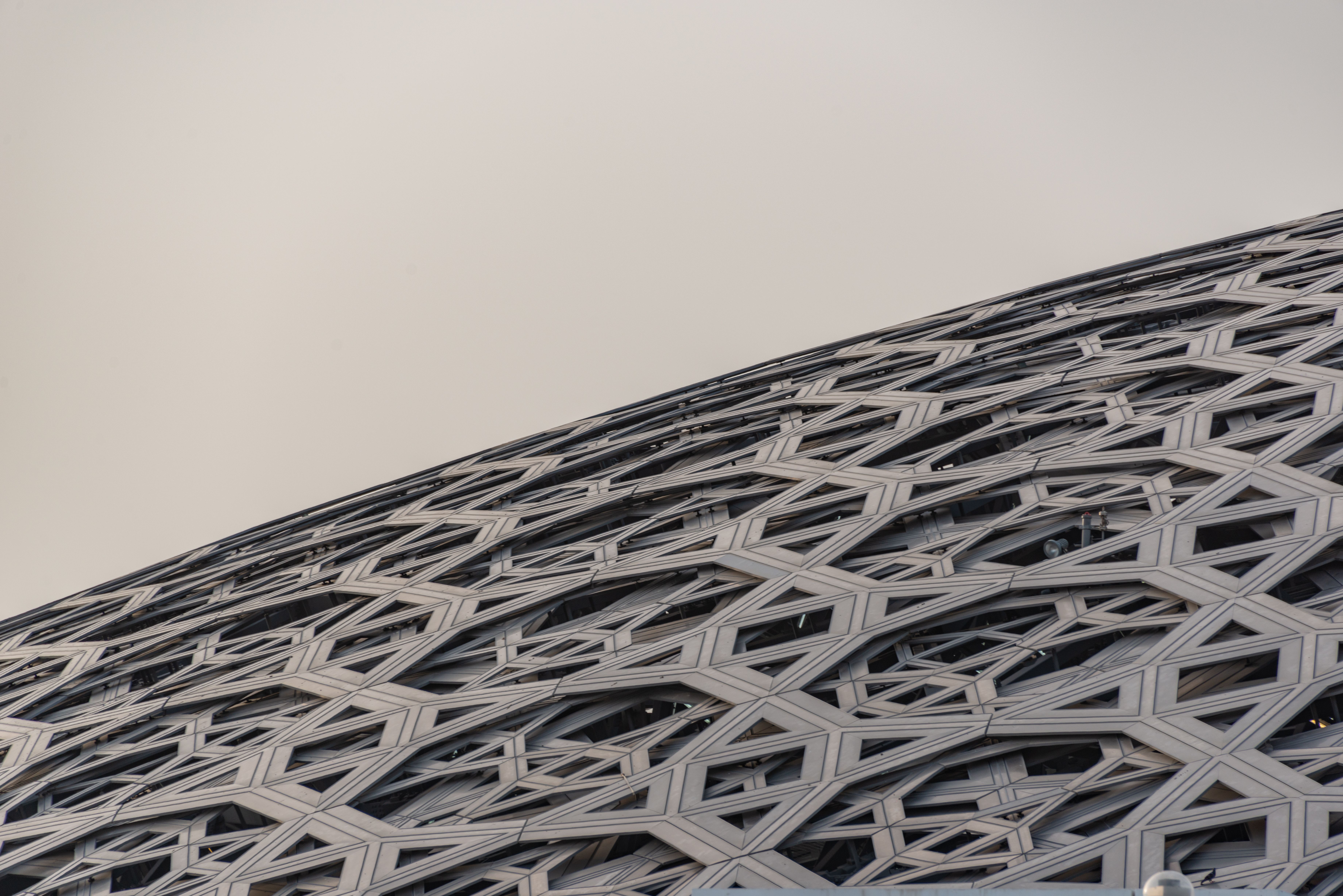 Close-up of the intricate geometric dome roof of Louvre Abu Dhabi, showcasing modern architecture.