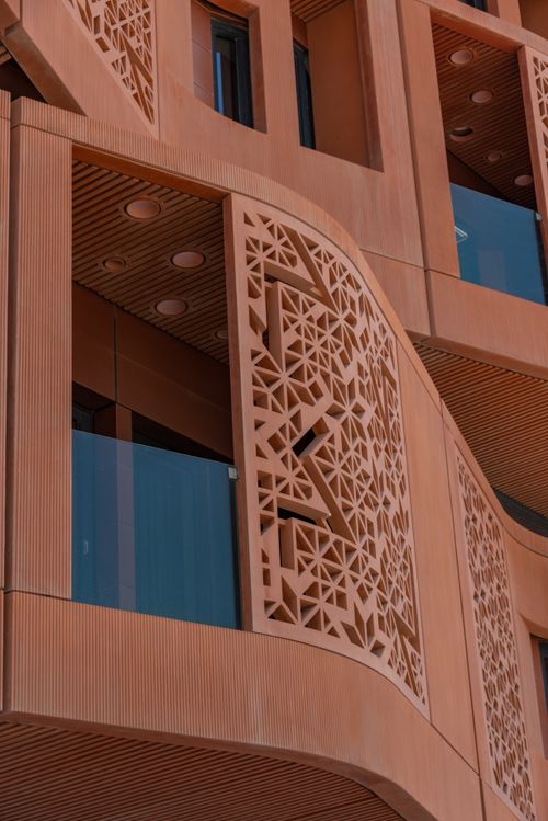 Free Close-up of a modern building facade showcasing intricate geometric patterns and glass elements. Stock Photo