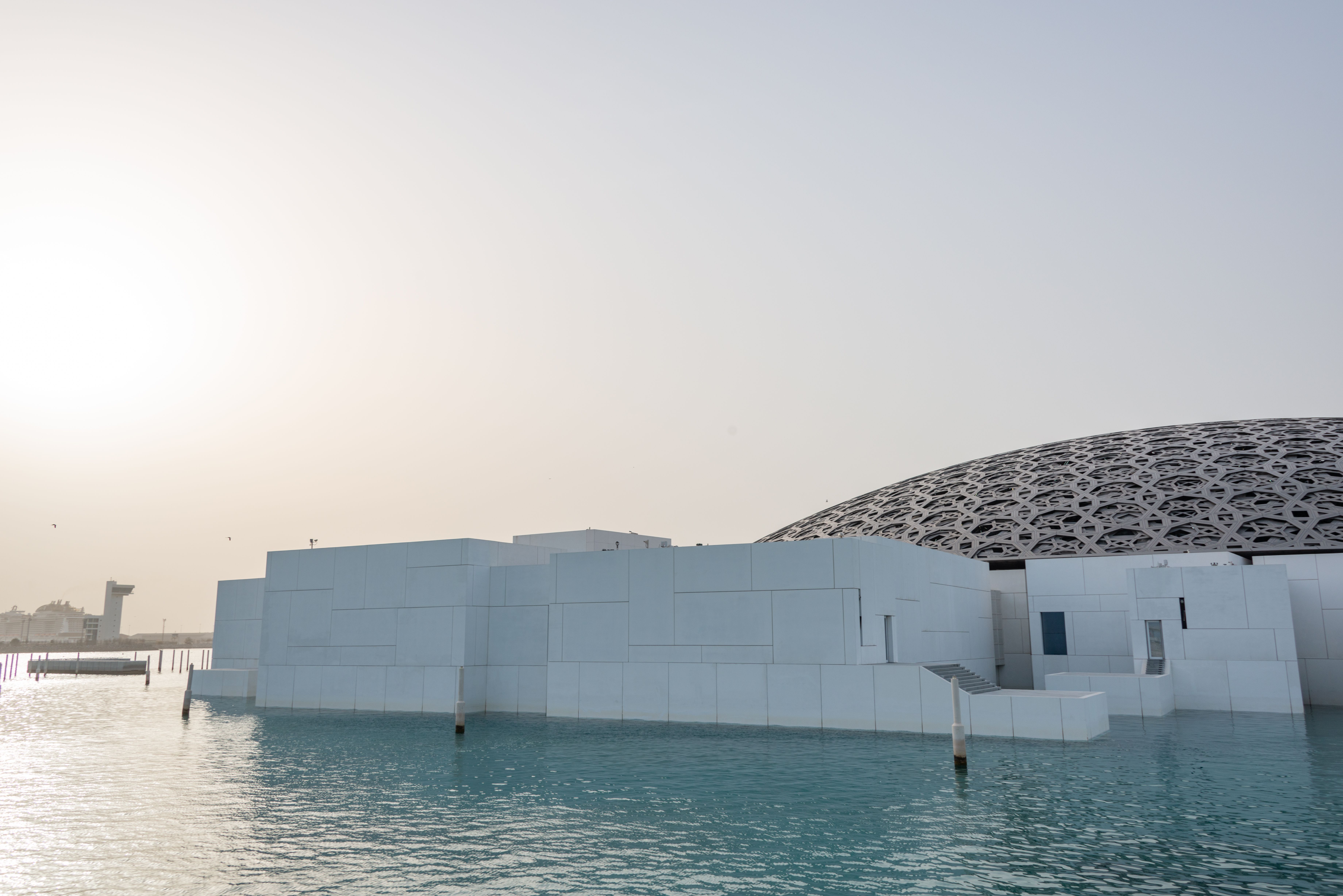A serene view of Louvre Abu Dhabi showcasing its unique dome and modern design.
