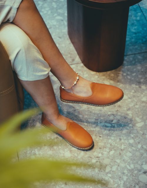 Free Elegant brown footwear showcased on a polished marble floor with a relaxed setting. Stock Photo