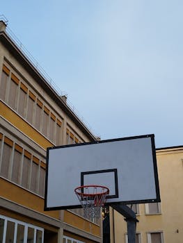 Outdoor basketball court with hoop and clear blue sky backdrop in Verona, Italy.