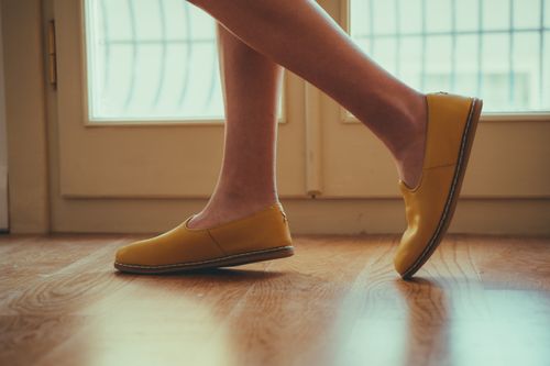 Free A close-up view of yellow shoes on a wooden floor inside a well-lit room. Stock Photo