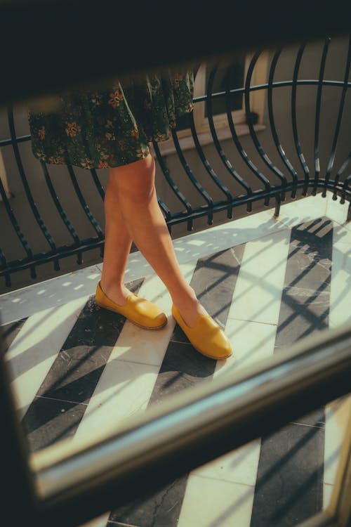 A Woman Wearing Yellow Shoes on a Balcony