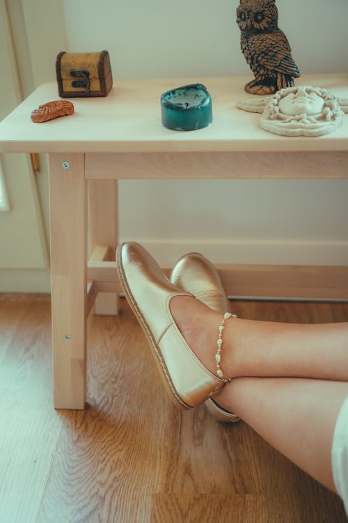 Woman Legs with Bracelet and Shoes on Floor under Table with Decorations