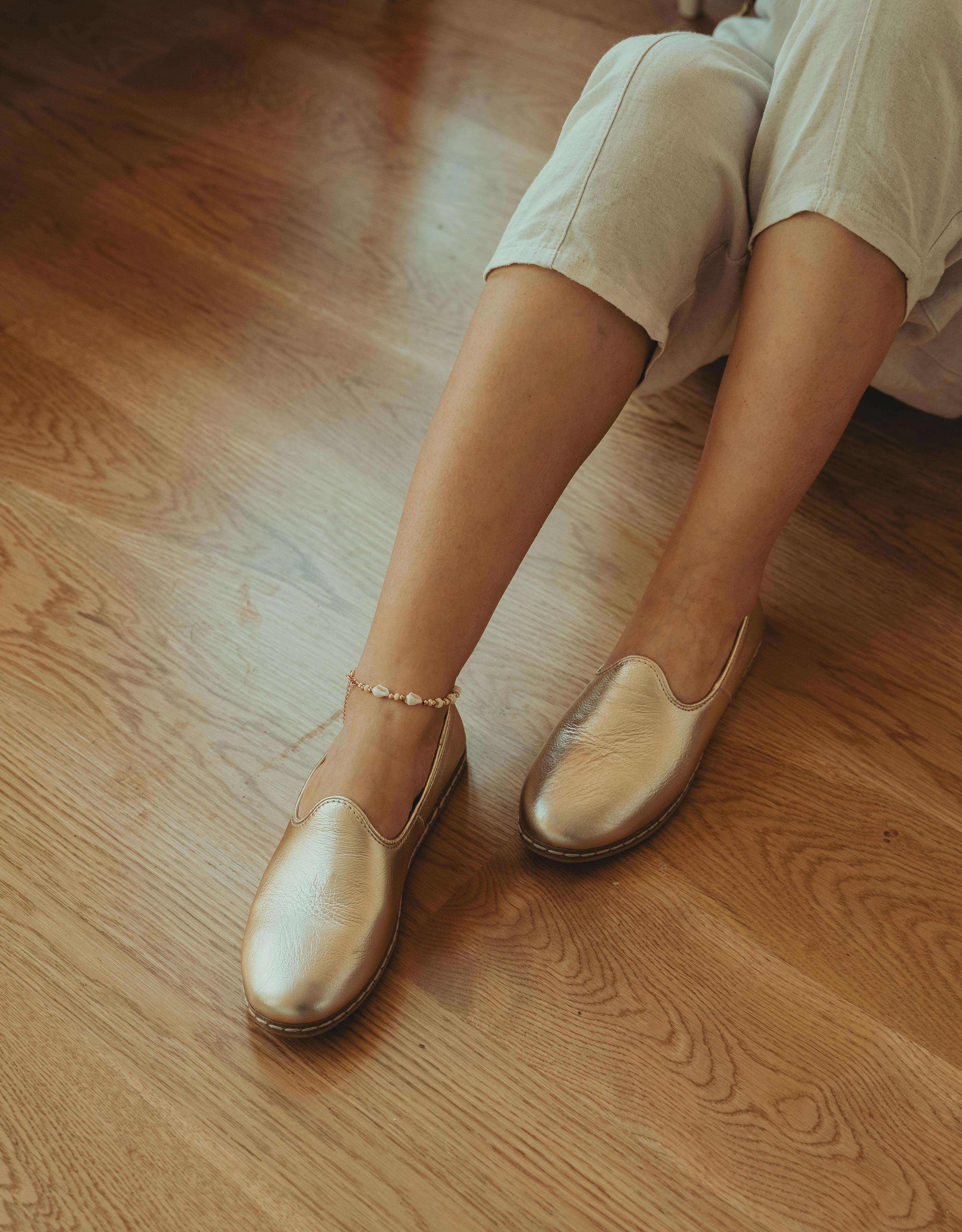Free Stylish woman wearing gold loafers and ankle bracelet on wooden floor. Stock Photo