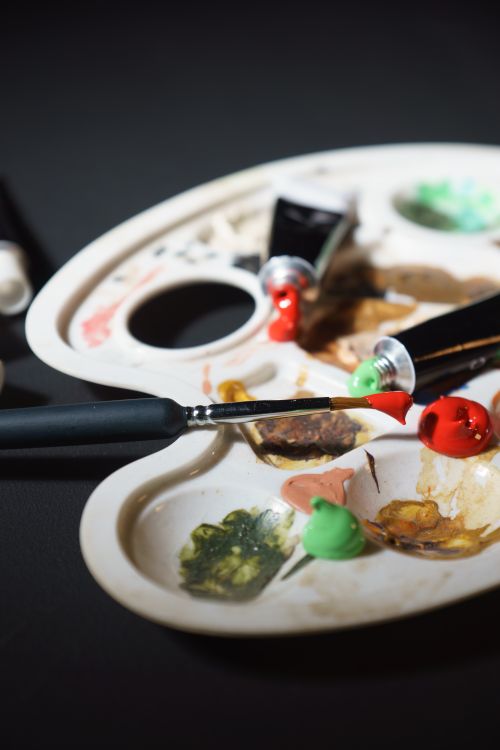 Free Artistic close-up of brushes and colorful palette against a dark background, ideal for creative projects. Stock Photo