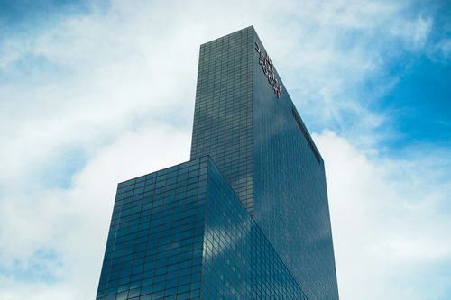 Free Low-angle view of a modern skyscraper in Rotterdam with reflective glass facade and blue sky. Stock Photo