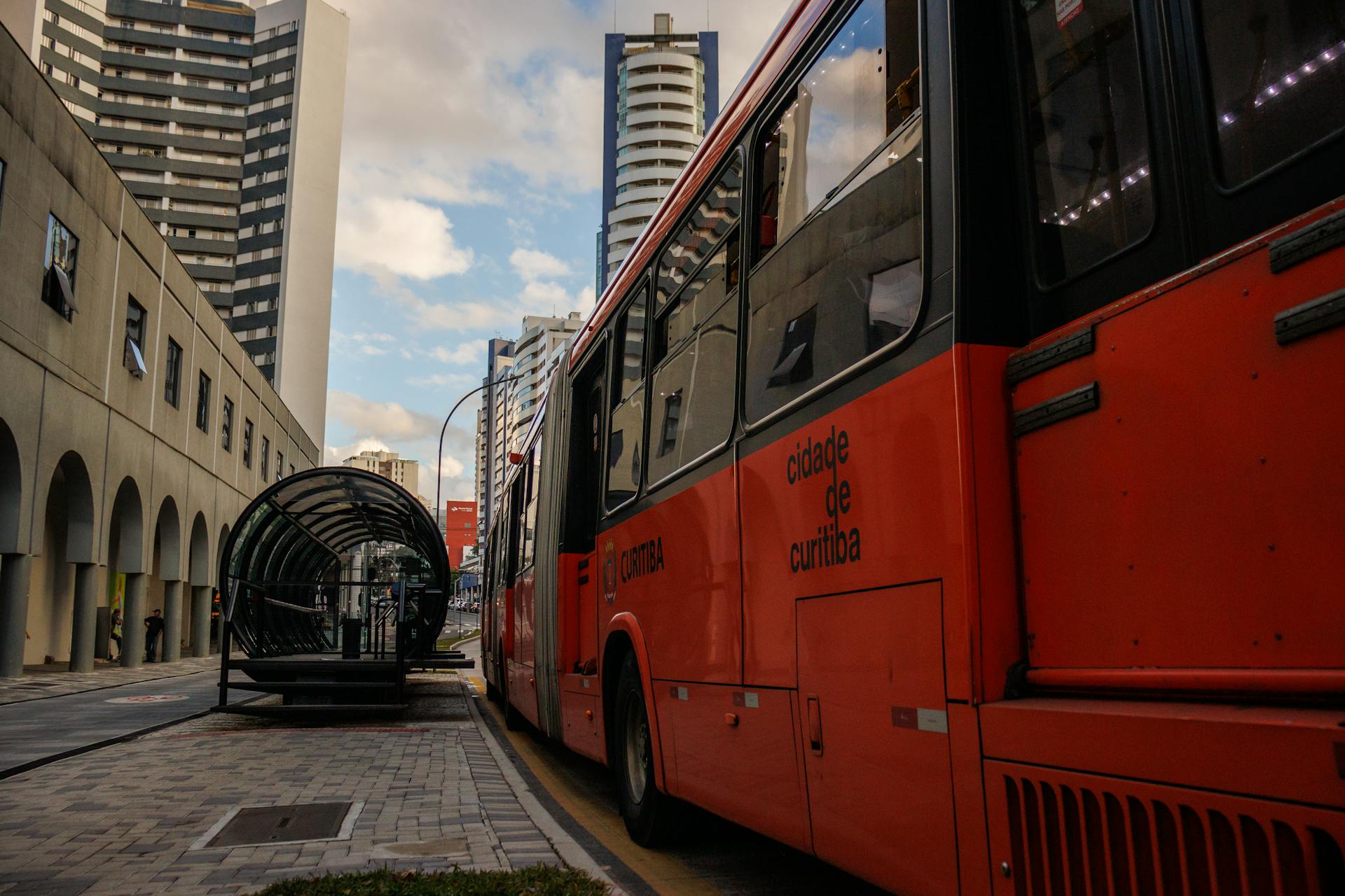 Red city bus at a modern stop in downtown Curitiba, showcasing urban transport.