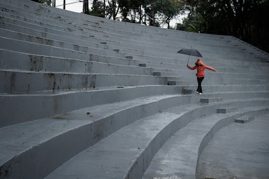 A woman with an umbrella walks up gray steps on a rainy day in Curitiba, Brazil.