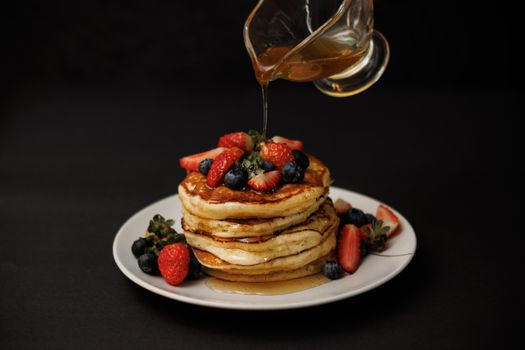 Mouthwatering stack of pancakes topped with fresh berries and drizzled with syrup, perfect for breakfast.