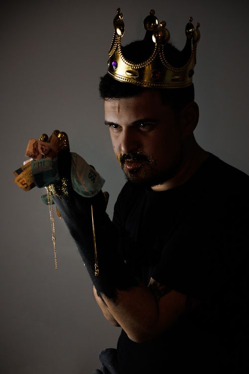 Free A man in a crown and dark settings holding cash, symbolizing power and wealth. Stock Photo