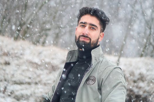 Portrait of a bearded man in a jacket during snowy winter outdoors, exuding a calm and serene vibe.