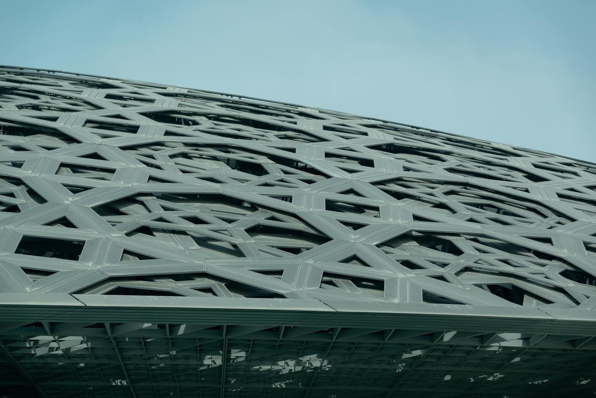 Close-up view of the modern architectural design of Louvre Abu Dhabi's roof structure.