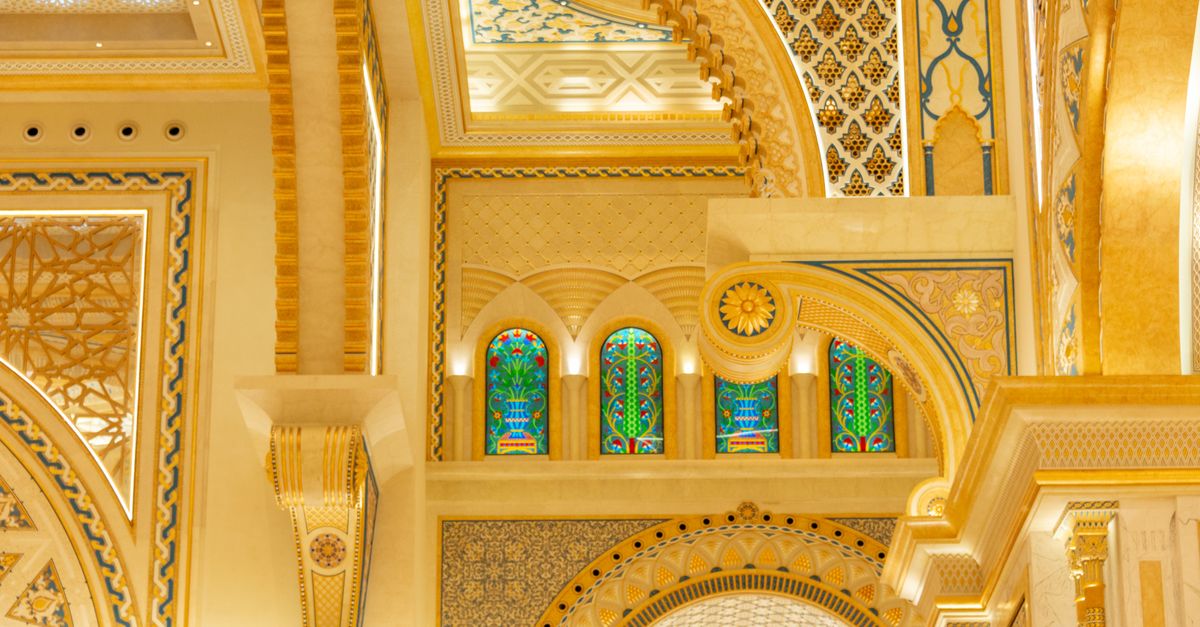 Captivating ornate ceiling inside a temple featuring gold accents and stained glass windows.