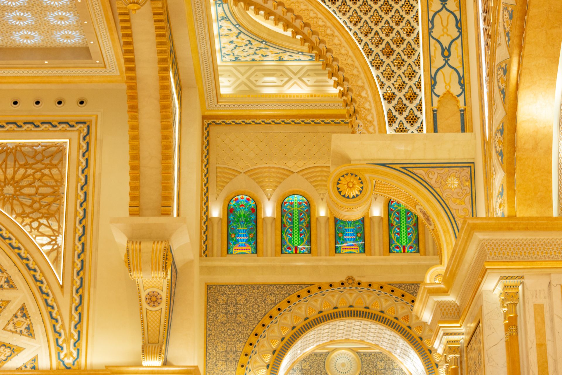 Captivating ornate ceiling inside a temple featuring gold accents and stained glass windows.