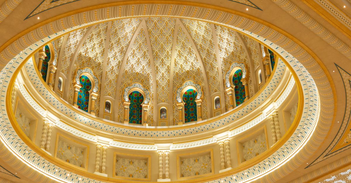Stunning interior view of a golden mosque dome showcasing intricate patterns and stained glass windo