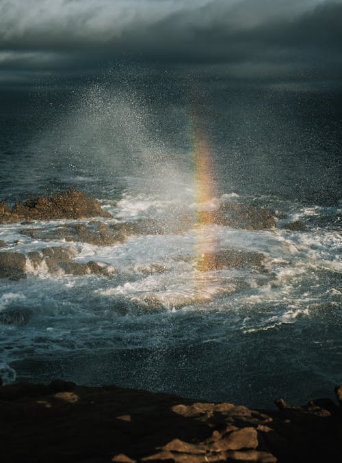 Rainbow over Sea Shore under Clouds