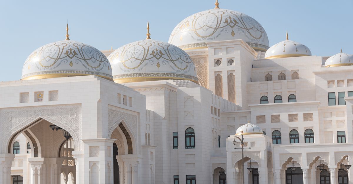 Captivating image of an elegant mosque with beautiful gold-adorned domes under clear blue skies.