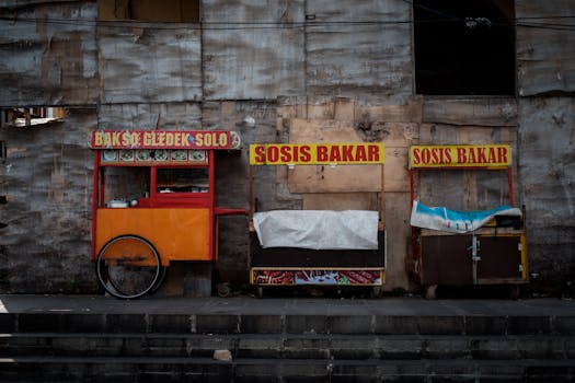Image of two colorful street food carts in an urban area, displaying local signs.