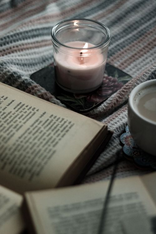 Free Relaxing atmosphere with an open book, lit candle, and coffee on a soft blanket. Stock Photo