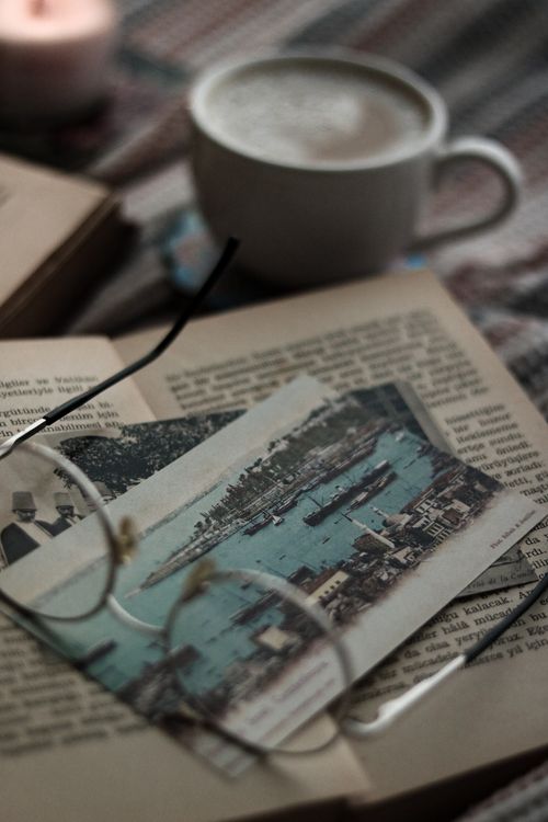 Free A warm, cozy still life featuring an open book, coffee, and eyeglasses creating a vintage vibe. Stock Photo