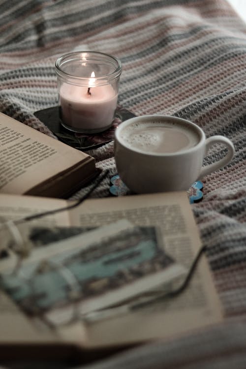 도자기 컵, 독서하는, 밝게 빛나는 양초의 무료 스톡 사진