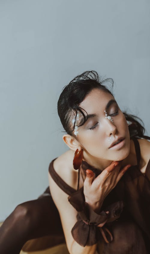 Brunette Woman with White Beads on Face Posing with Eyes Closed