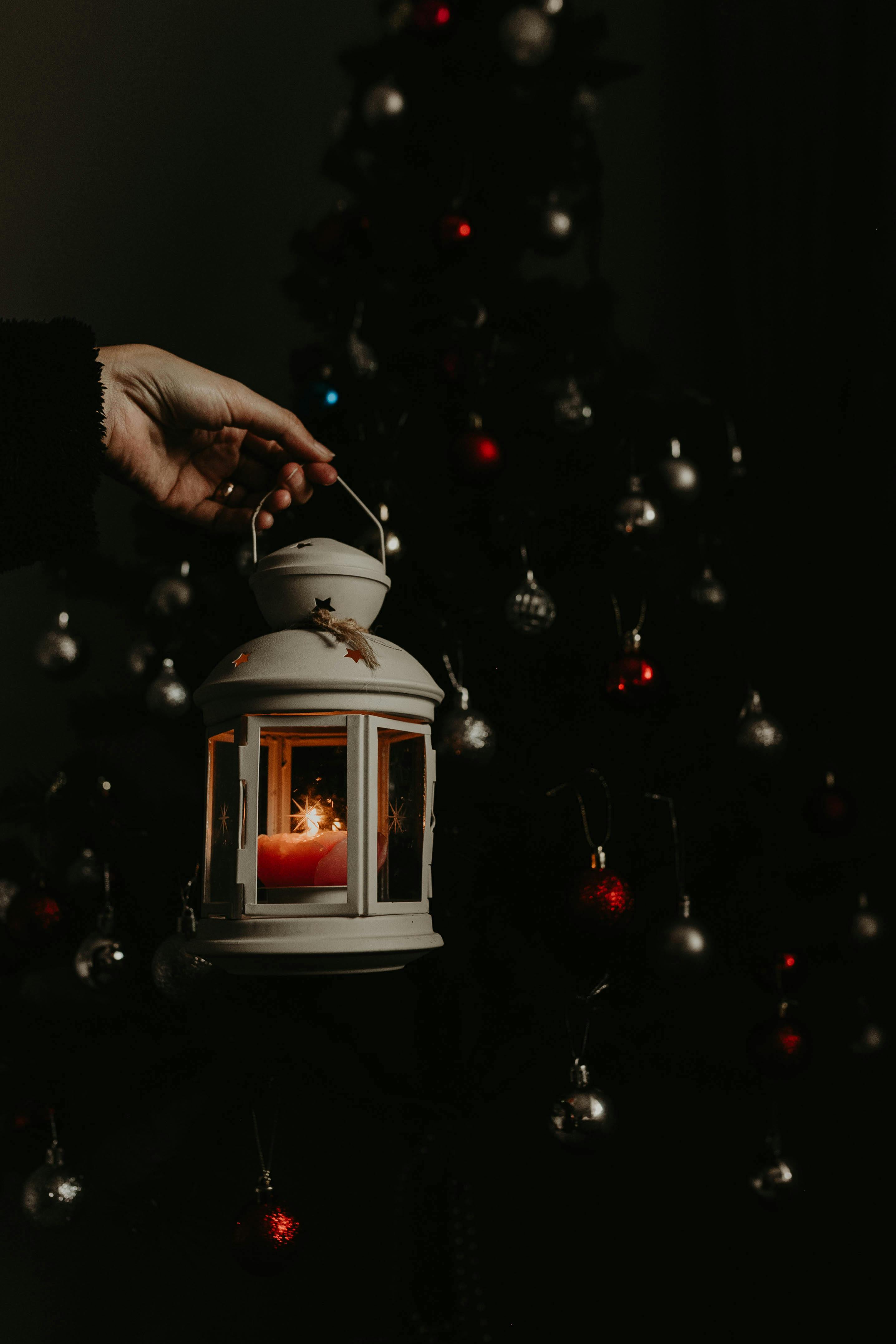 a person holding a lantern in front of a christmas tree