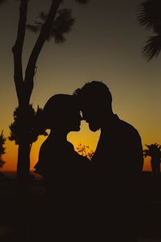 Silhouette of a romantic couple kissing during sunset creating an intimate and moody atmosphere.