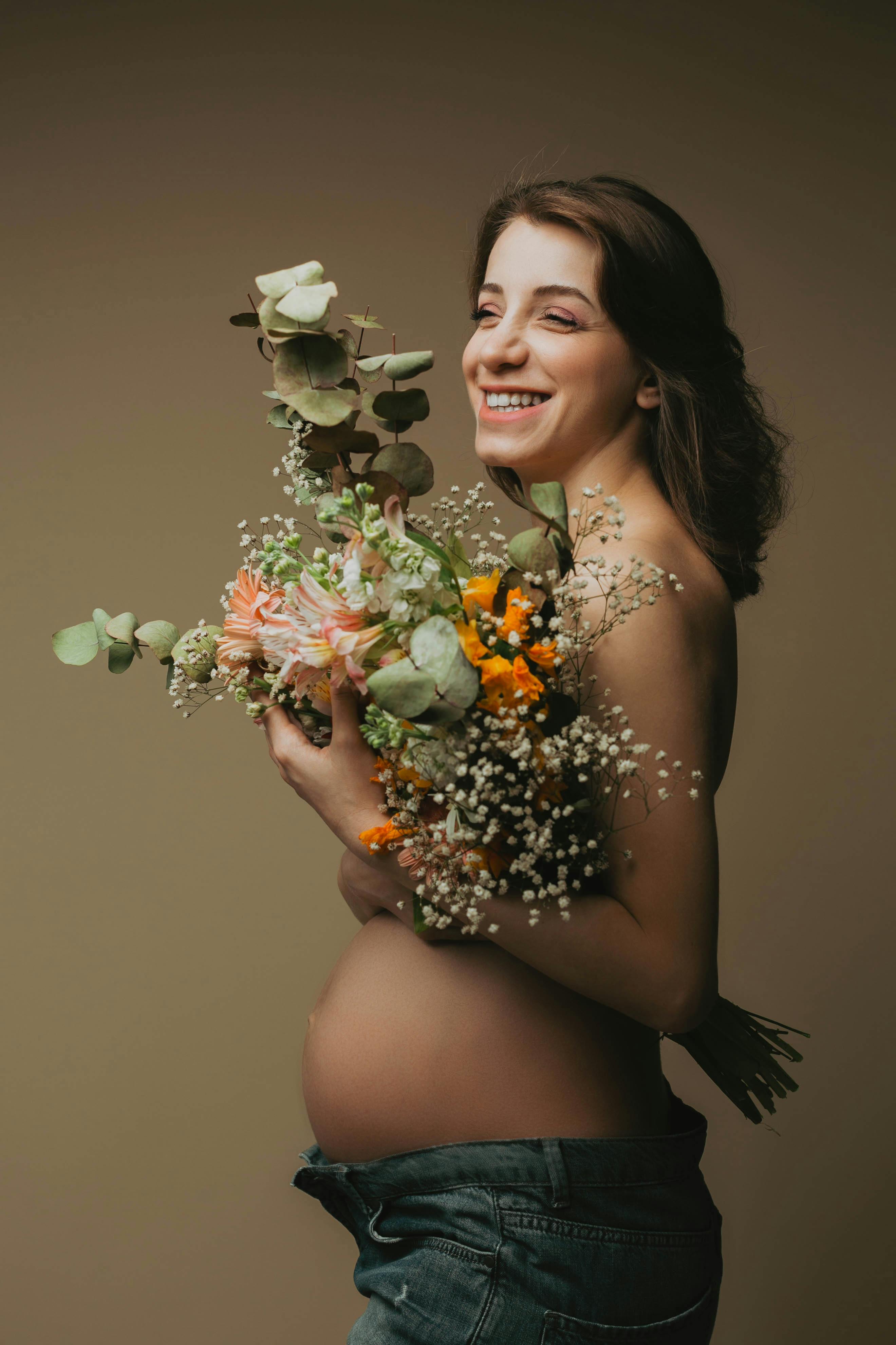 smiling pregnant woman holding a bouquet of flowers