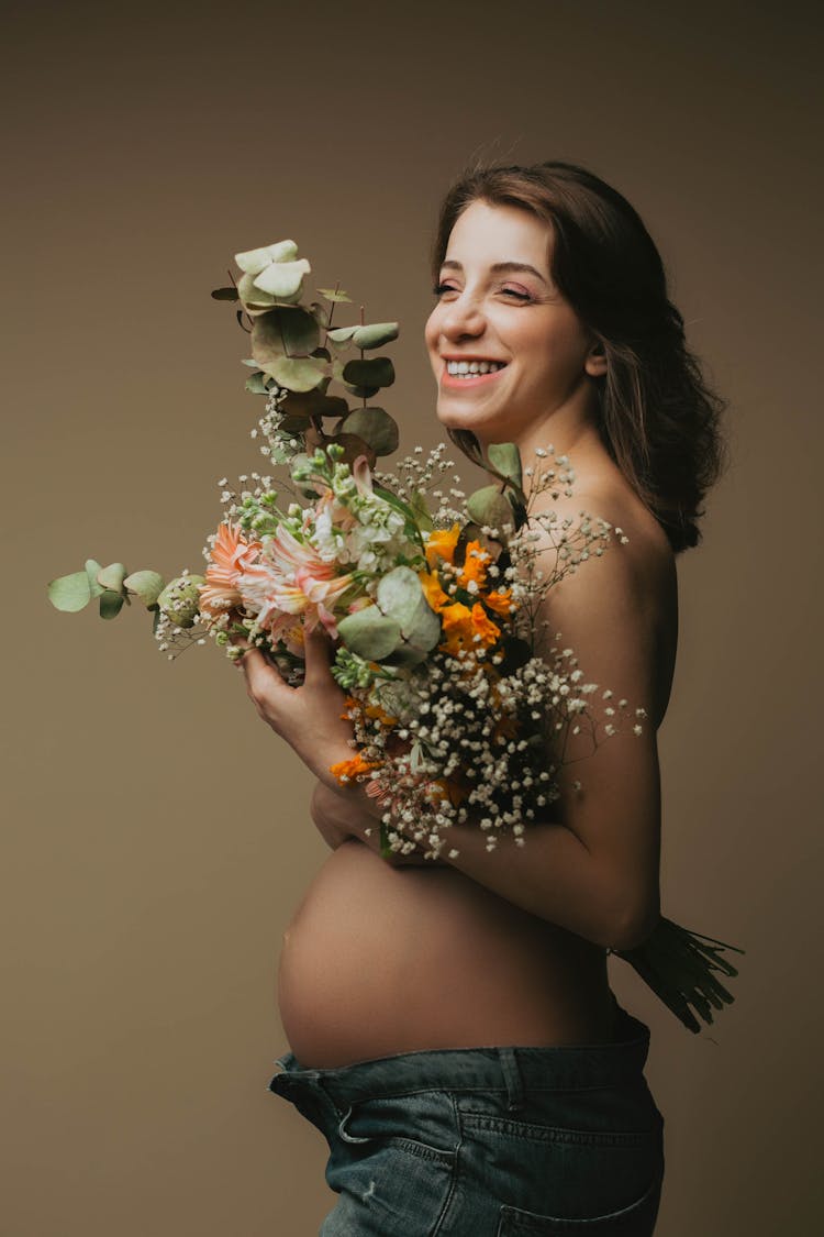 Smiling Pregnant Woman Holding A Bouquet Of Flowers