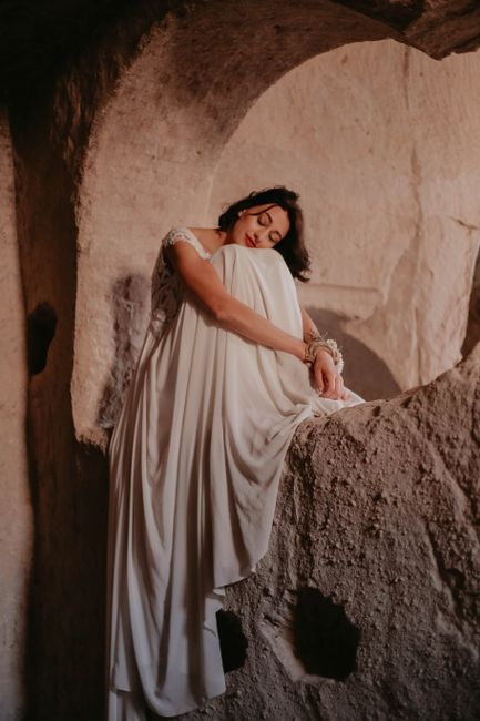 A serene portrait of a woman in a white dress resting peacefully inside a cave.