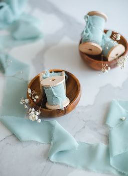 Elegant still life of wooden spools and fabric with baby's breath flowers.