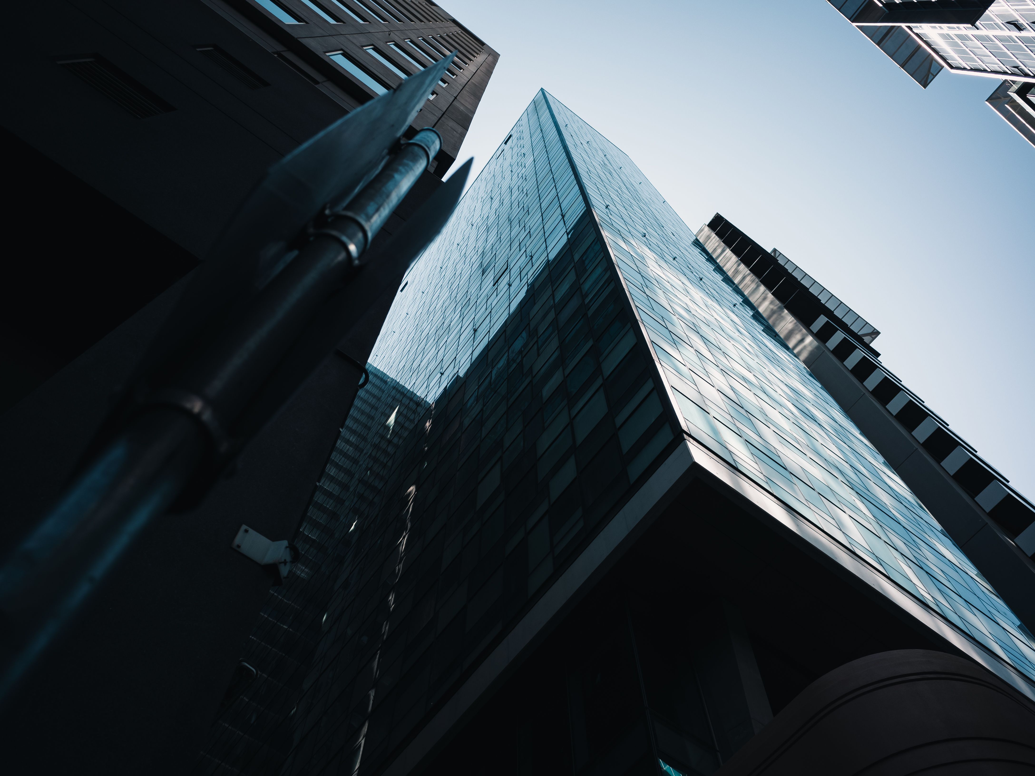 A dramatic view of a modern skyscraper's glass facade under a clear blue sky.