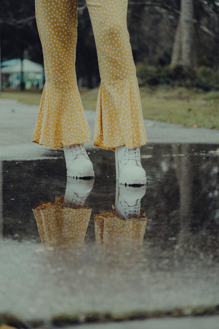 A Person Wearing White Boots On Wet Ground