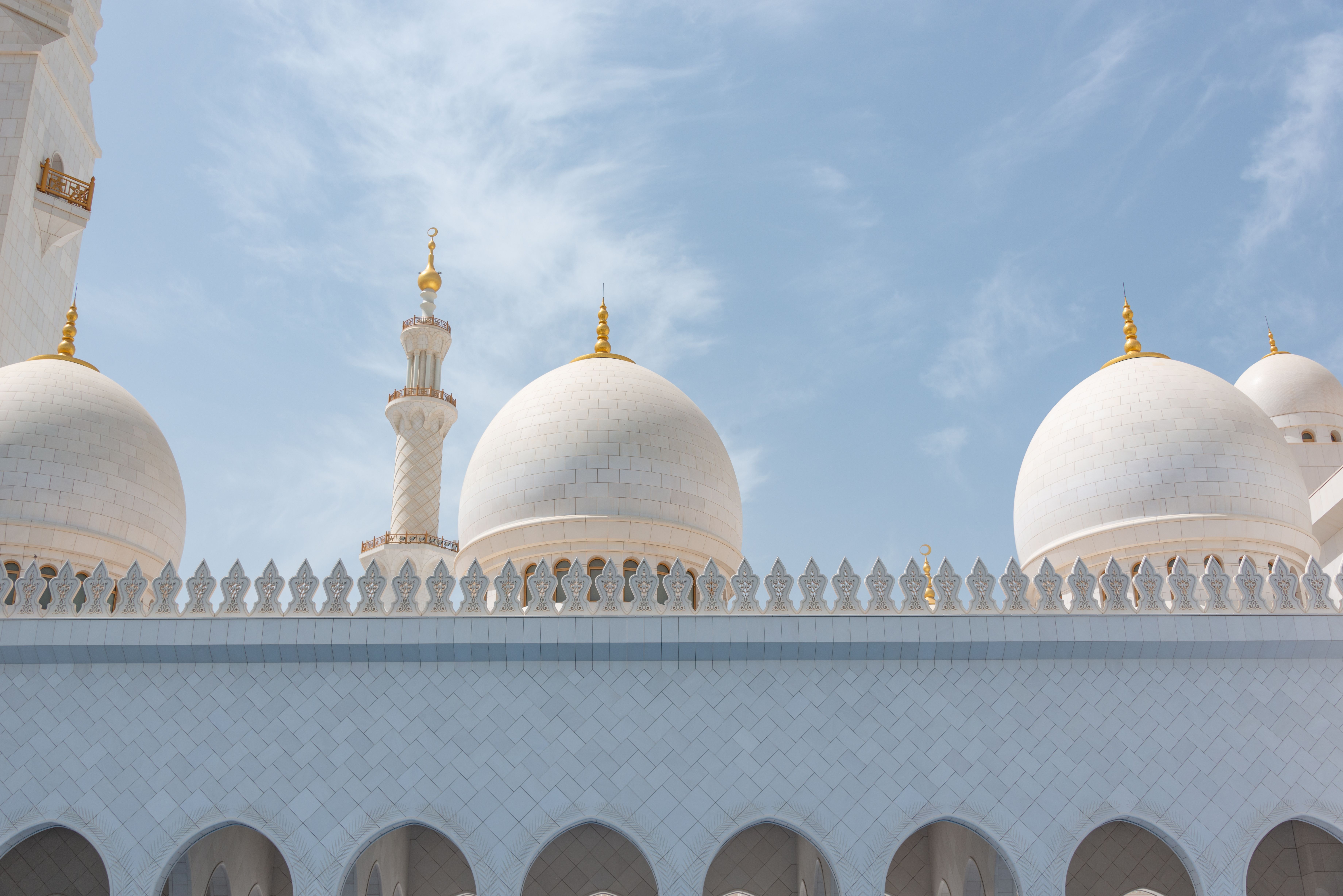 Low angle view of the stunning domes of Sheikh Zayed Grand Mosque under a clear blue sky.