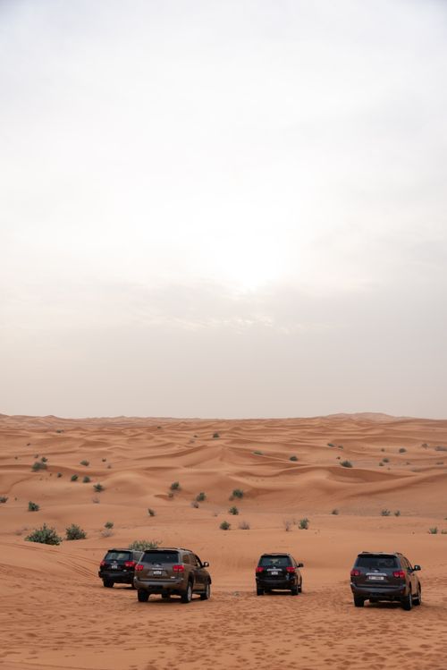 Free Four SUVs exploring the vast and picturesque desert dunes under a clear sky. Stock Photo