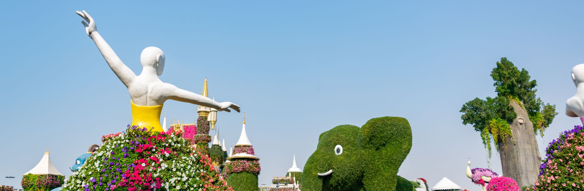 Vibrant floral sculptures and topiaries in Dubai Miracle Garden on a sunny day.