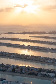 Stunning aerial view of Palm Jumeirah with sun setting over the sea, capturing the iconic layout.