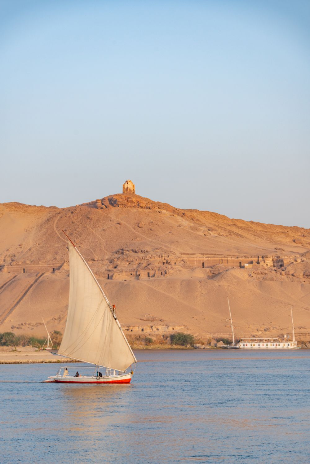 Felucca navegando o Nilo diante das colinas de Aswan
