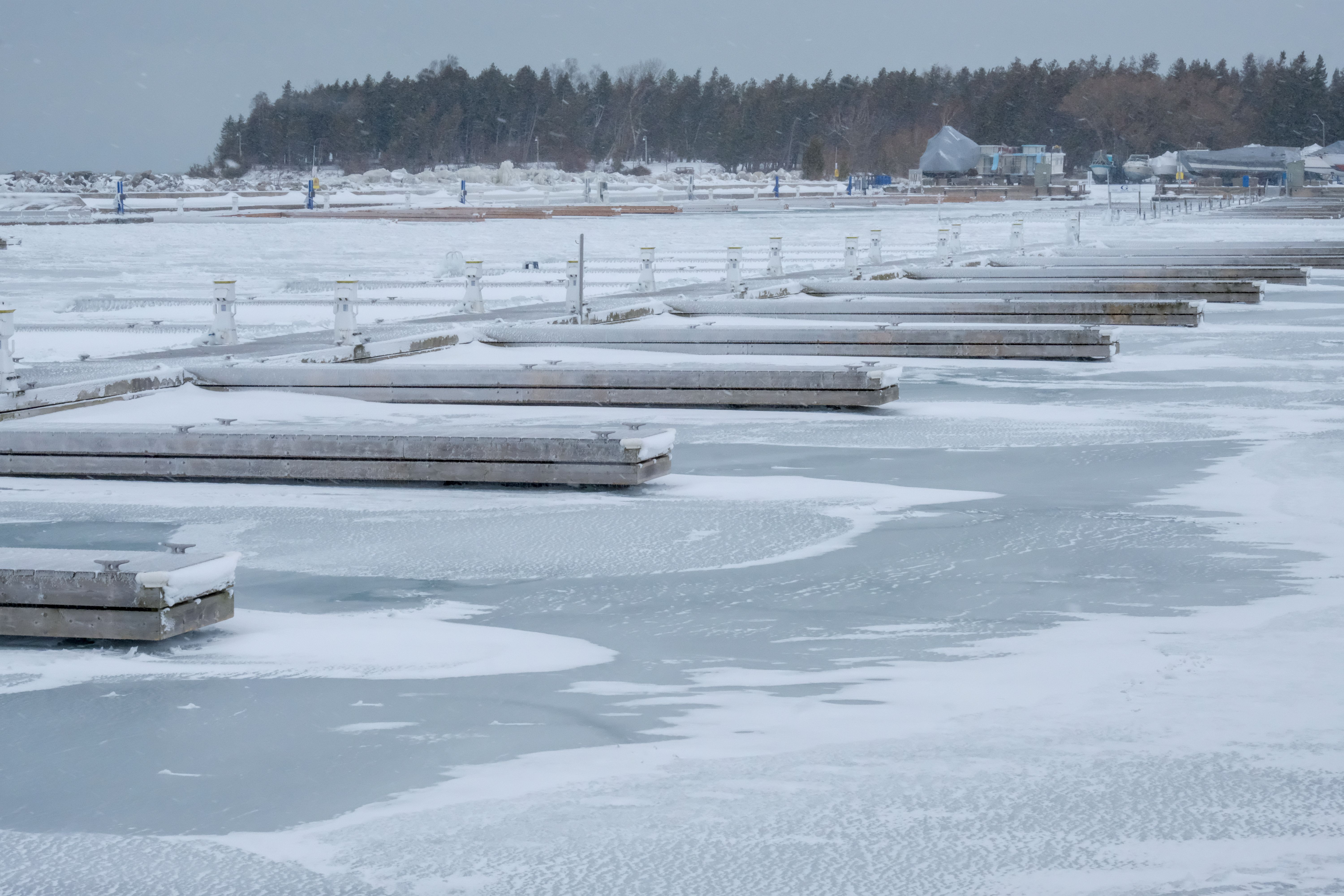Snow-covered marina with frozen lake in Ontario, Canada during winter.
