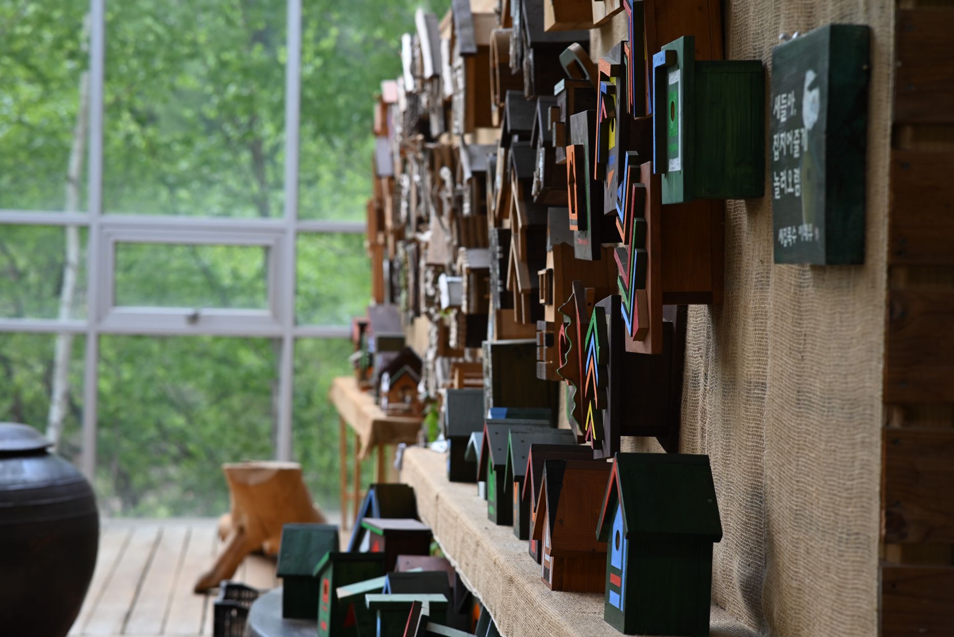 Vibrant display of handmade wooden birdhouses in an indoor green setting.