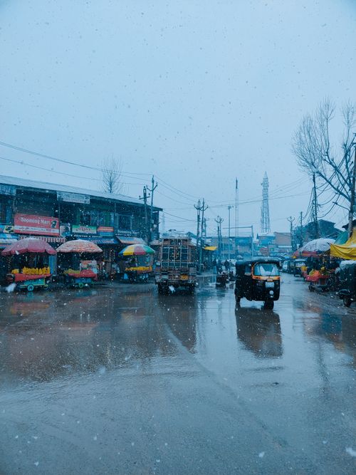 Free City street in winter with snowfall, colorful market stalls, and traffic. Stock Photo