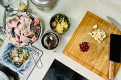 Overhead shot of a kitchen counter with chopped garlic, chicken, and various ingredients for cooking preparation.