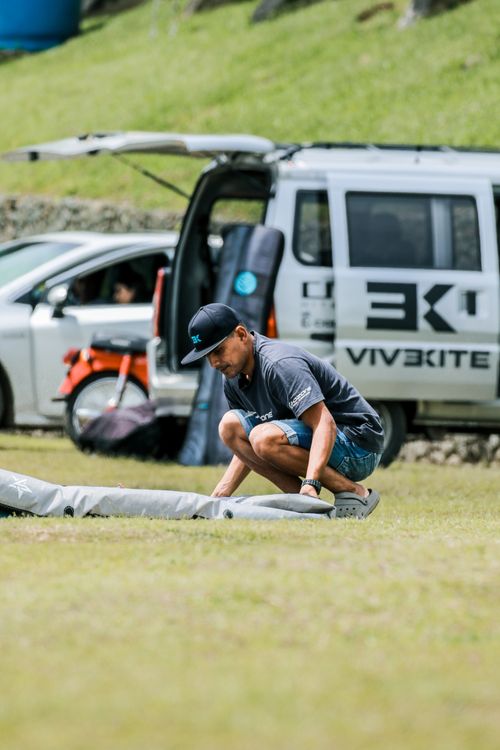 Free Man setting up kiteboarding gear by a van on a sunny day at the seaside. Stock Photo