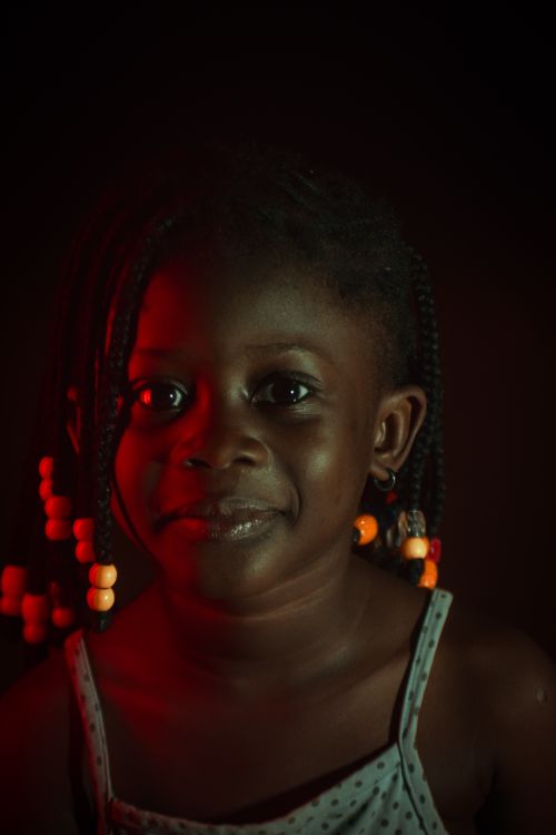 Free Close-up portrait of a smiling young girl with braided hair and colorful beads. Stock Photo
