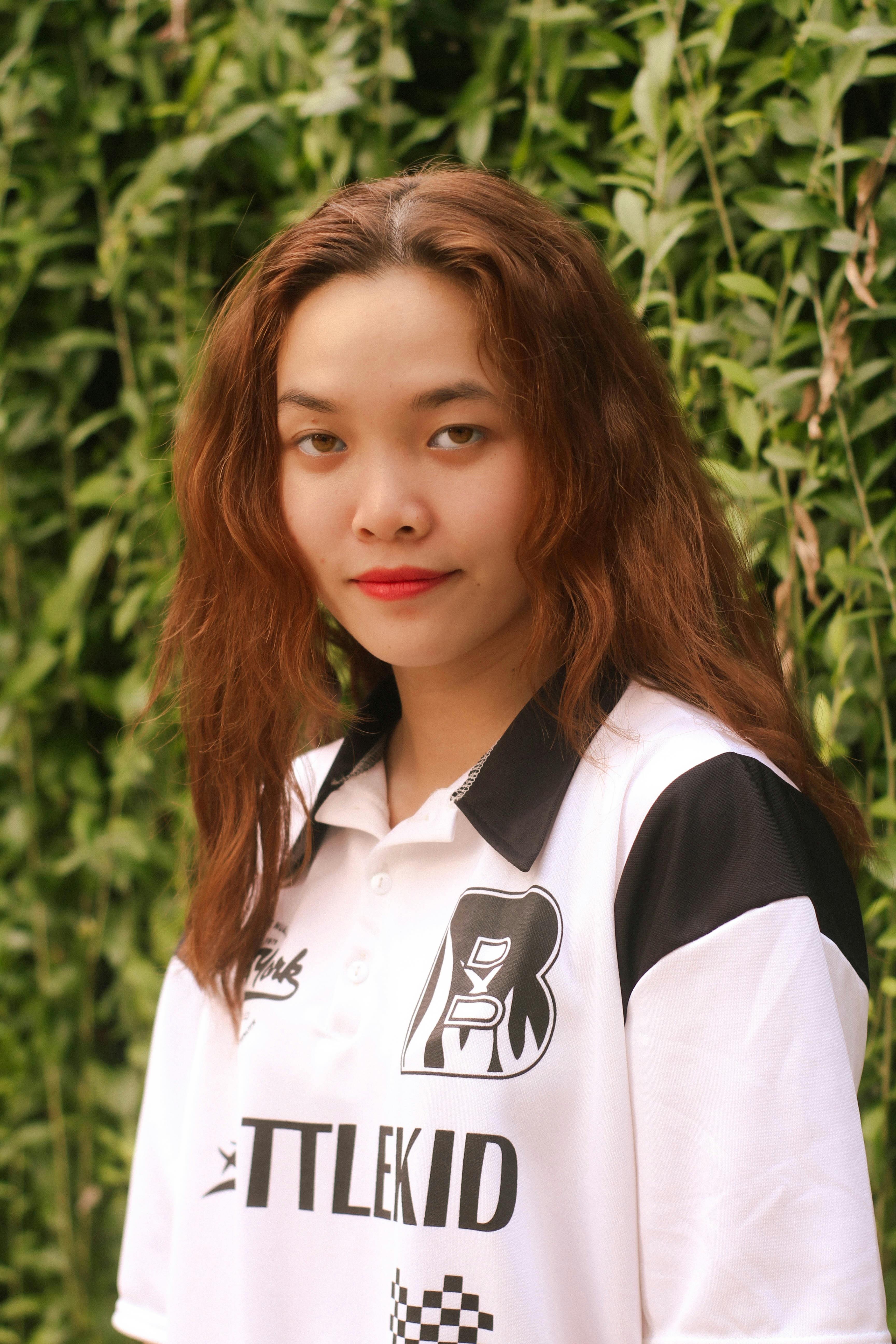 Teenage girl with red lipstick poses confidently in a stylish black and white shirt outdoors.
