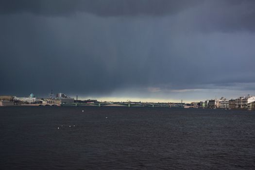 Stormy sea with dark clouds over an urban skyline, capturing a dramatic weather scene.